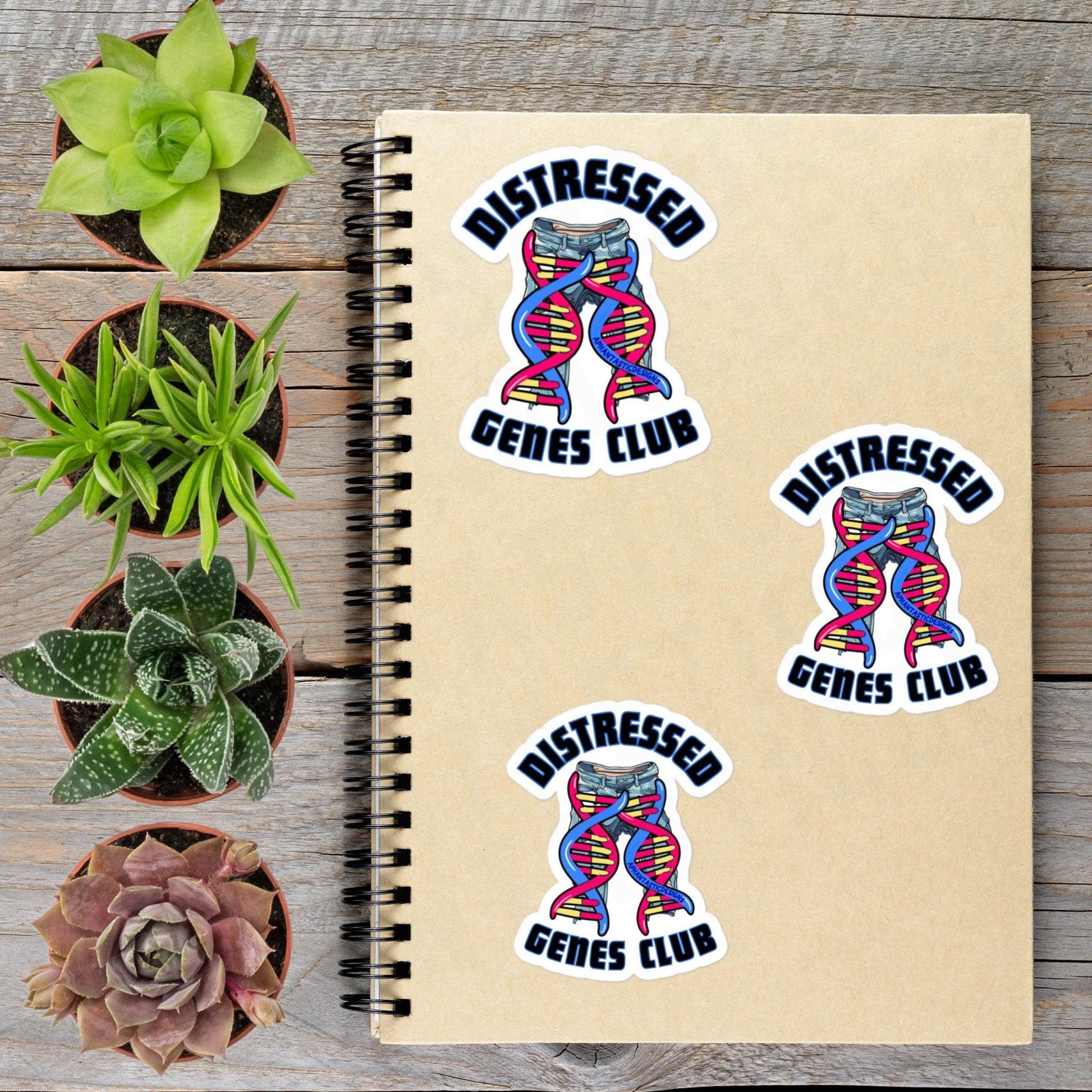 a notebook with three stickers on it, along with several potted plants arranged around it.
