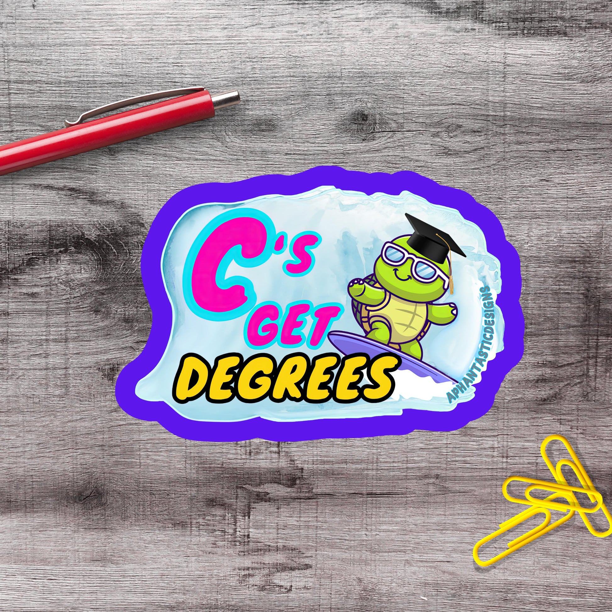 a sticker with a cartoon turtle and the text "C's GET DEGREES" on a wooden surface.