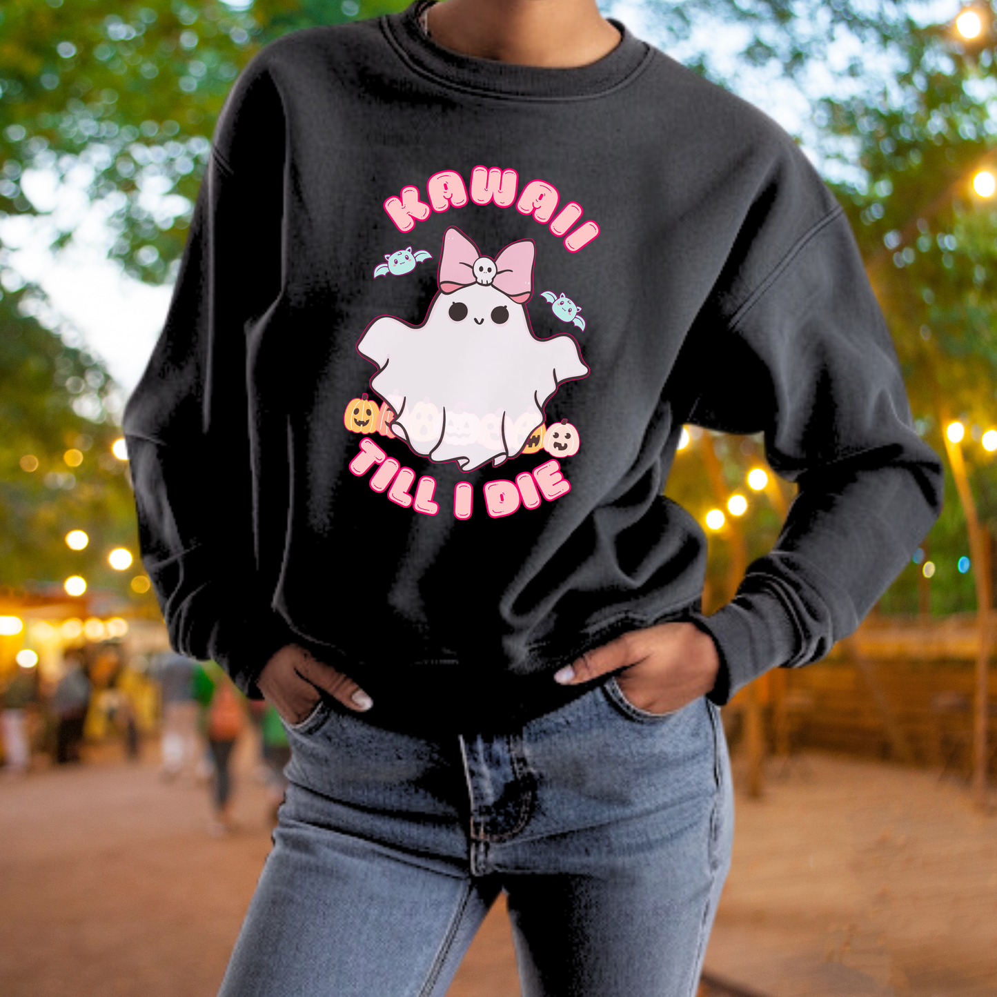 A person wearing a black sweatshirt with a graphic design featuring a ghost and the text "Kawaii Till I Die".