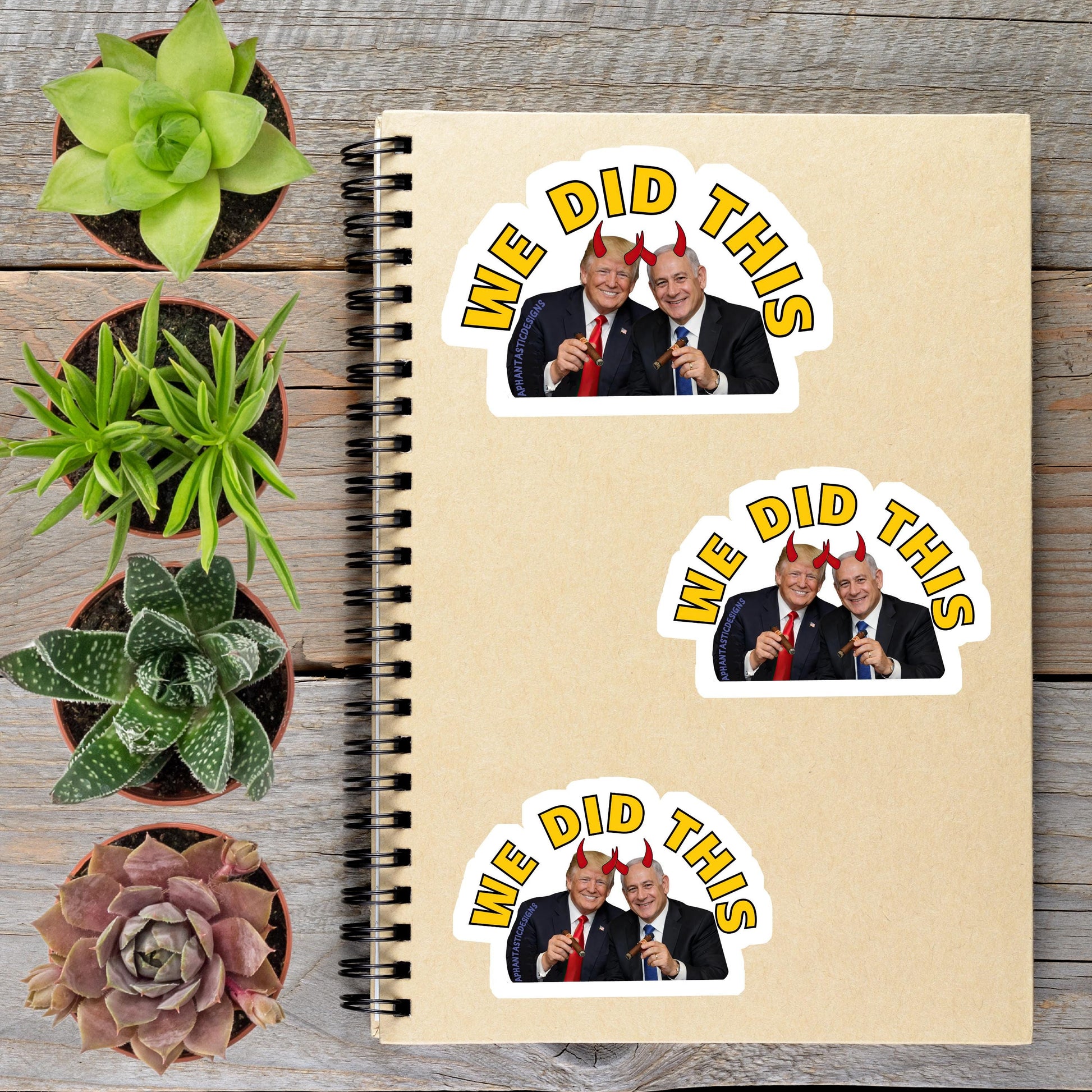 a spiral notebook with stickers on it, along with several potted plants arranged on a wooden surface.
