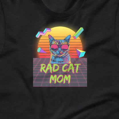 A graphic design on a black t-shirt featuring a cat wearing sunglasses, with a retro-style sunset in the background and the text "RAD CAT MOM" below the cat.