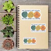 a notebook with stickers on it, along with four potted succulent plants arranged on a wooden surface.