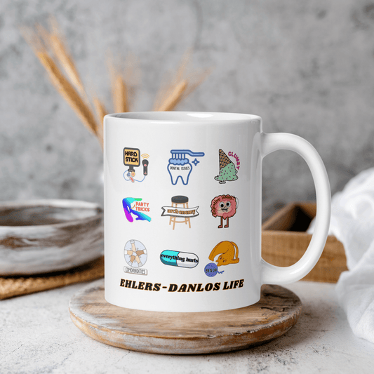 A white mug with various colorful and whimsical illustrations printed on it, placed on a wooden coaster.