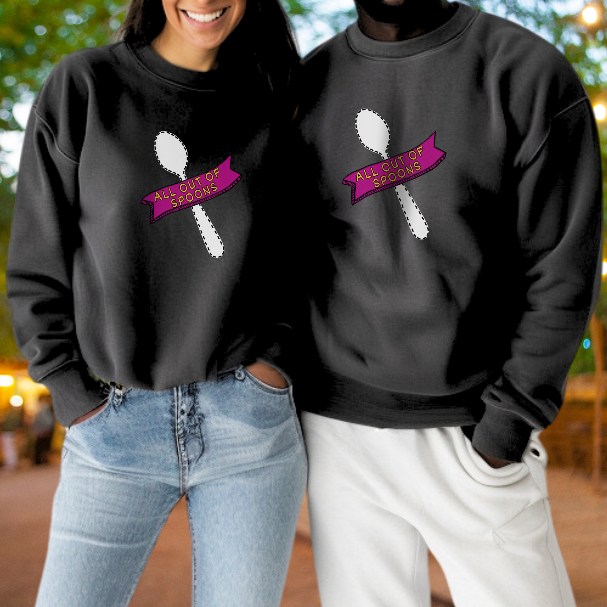 A woman and a man are standing next to each other, both wearing black sweatshirts with a graphic design featuring a spoon and a pink banner with the text "ALL OUTSOURCES".