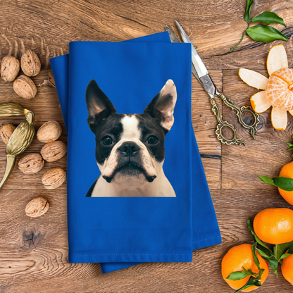 A blue towel with a picture of a dog is placed on a wooden surface, surrounded by various fruits such as oranges and walnuts.