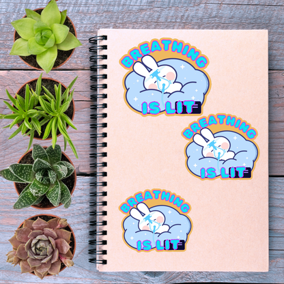 a spiral notebook with three stickers on it, along with several potted plants arranged on a wooden surface.