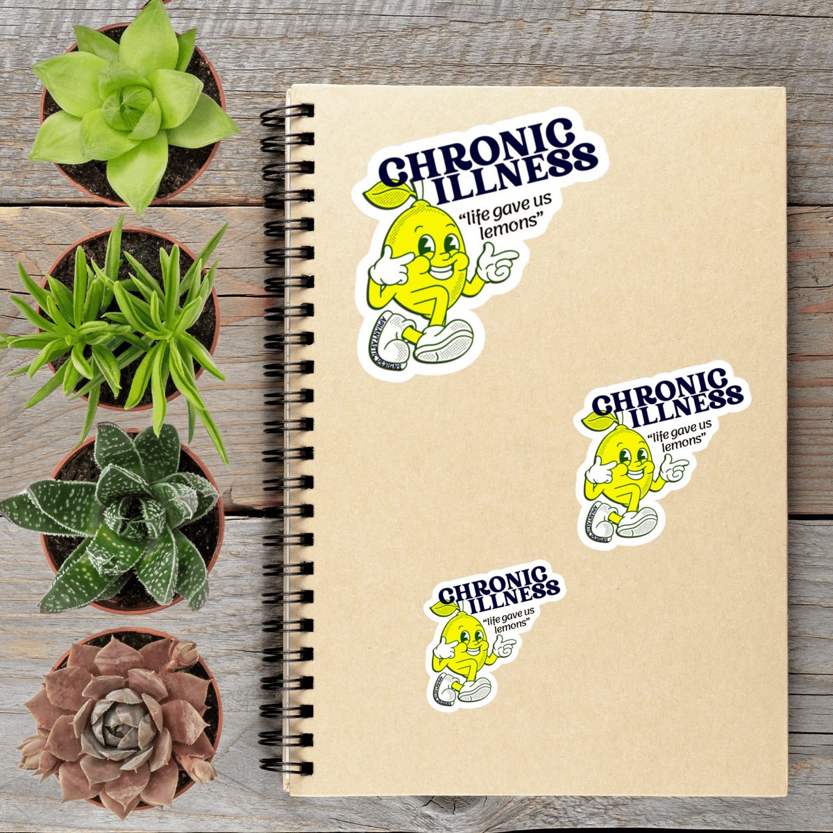 a notebook with stickers on it, along with several potted plants arranged on a wooden surface.
