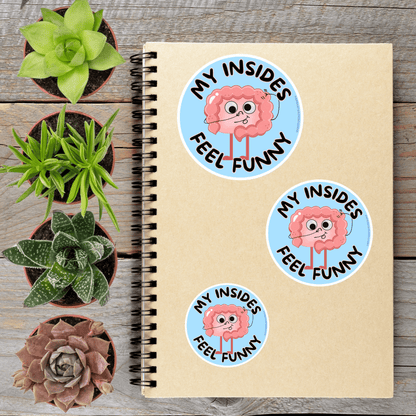 a spiral notebook with stickers on it, surrounded by four potted plants.