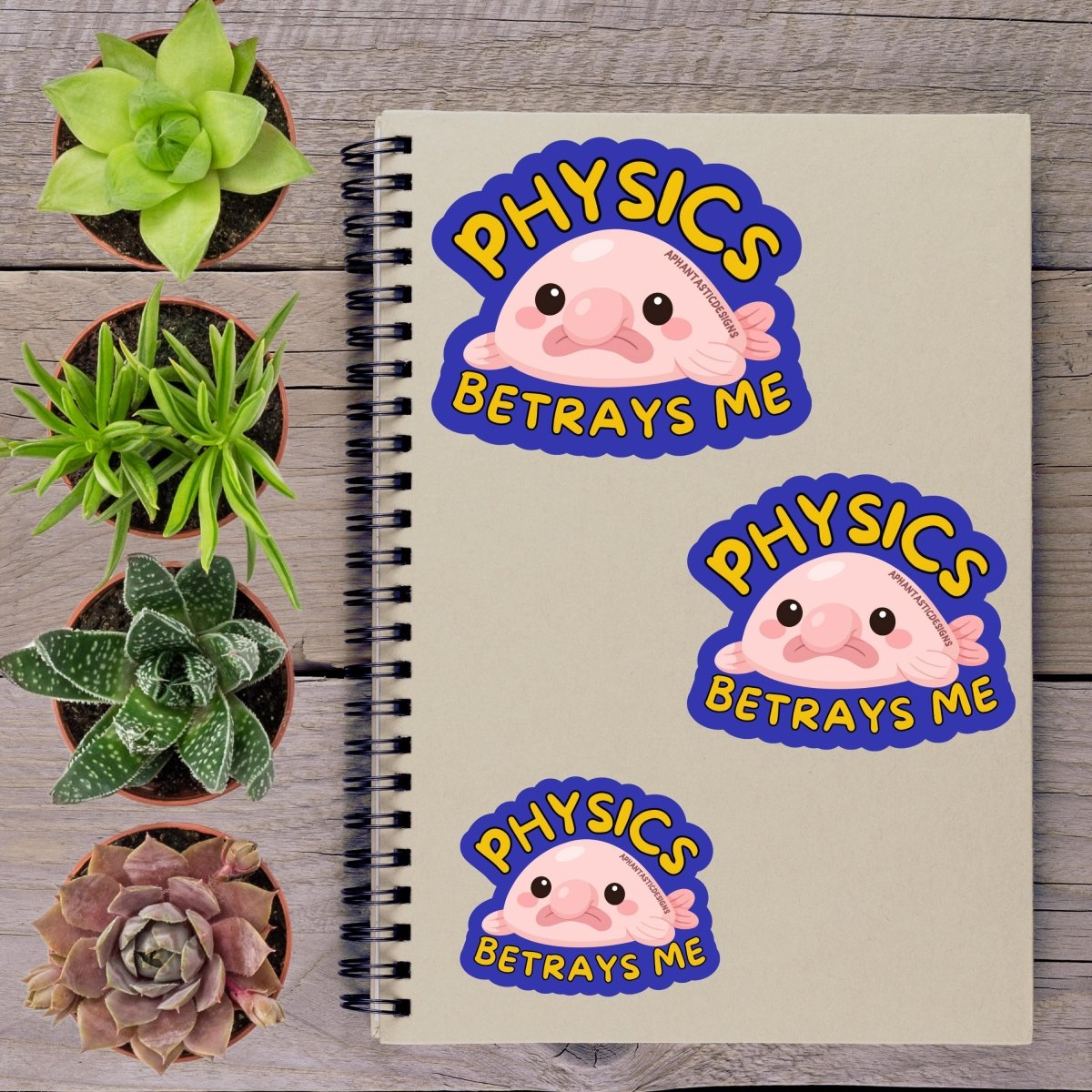a notebook with three stickers on it, along with several potted plants arranged on a wooden surface.