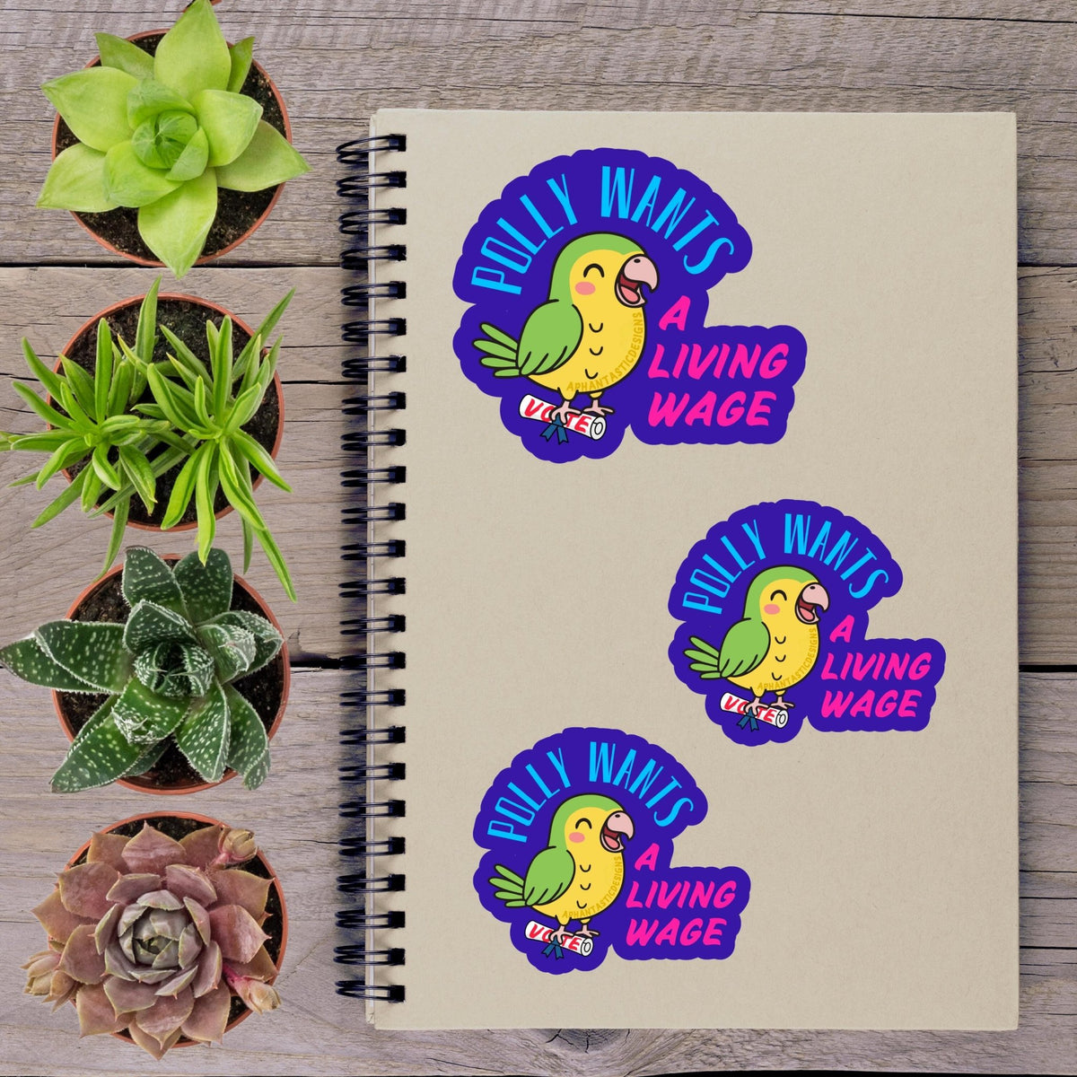 a spiral notebook with stickers on it, along with several potted plants arranged on a wooden surface.