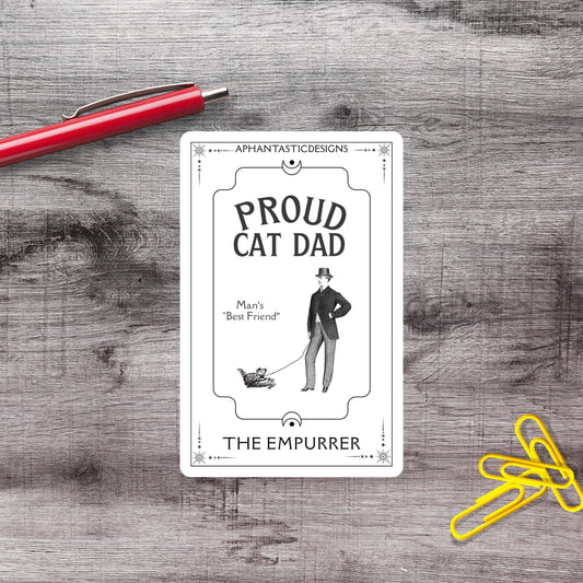 a card with a man and a cat, along with a red pen and yellow paper clips on a wooden surface.