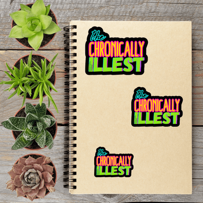 a spiral notebook with three stickers on it, along with four potted succulent plants arranged on a wooden surface.