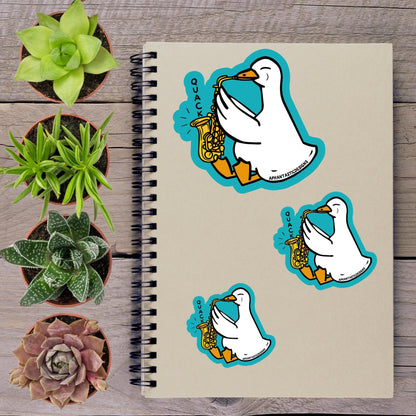 a notebook with a sticker of a cartoon duck playing a saxophone, surrounded by potted plants and a spiral-bound notebook.